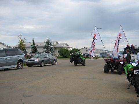 1995 Ford Bronco - An ATV performs a wheelie while participating in a parade, accompanied by other vehicles and flags.