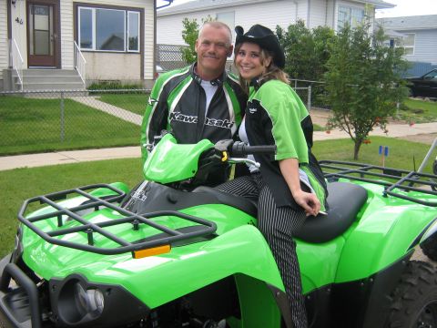 1995 Ford Bronco - A man and woman pose on a bright green ATV, both sporting Kawasaki branded jackets.