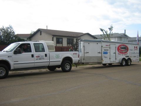 1995 Ford Bronco - A white pickup truck is seen towing a white trailer down a residential street.