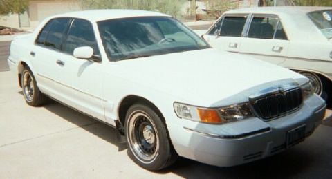2001 Mercury Grand Marquis - A white sedan is parked on a concrete surface, with another white vehicle behind it.