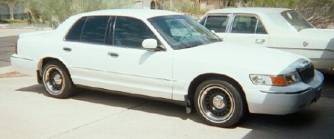 2001 Mercury Grand Marquis - A white 2001 Mercury Grand Marquis is parked next to another white sedan.