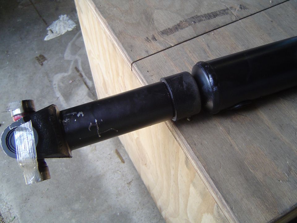 Black shock absorber with mounting bracket on plywood in a garage