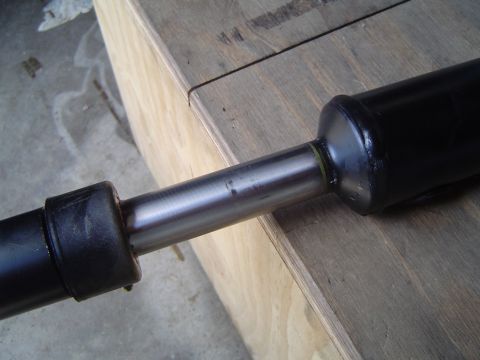 1989 Ford Bronco - A close-up view of a vehicle's driveshaft component, showing its metallic shaft and protective rubber boots.