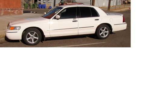 2001 Mercury Grand Marquis - A white sedan is parked on a street, viewed from the side.