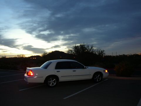 2001 Mercury Grand Marquis - A white sedan is parked in a lot under a cloudy sky at dusk.