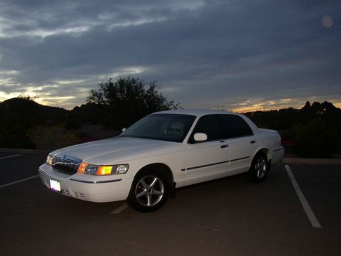 2001 Mercury Grand Marquis - A white 2001 Mercury Grand Marquis is parked in a lot under a cloudy sky at dusk.