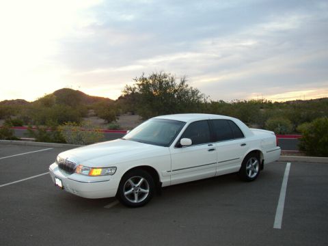2001 Mercury Grand Marquis - A white 2001 Mercury Grand Marquis is parked in a lot with a desert landscape in the background.