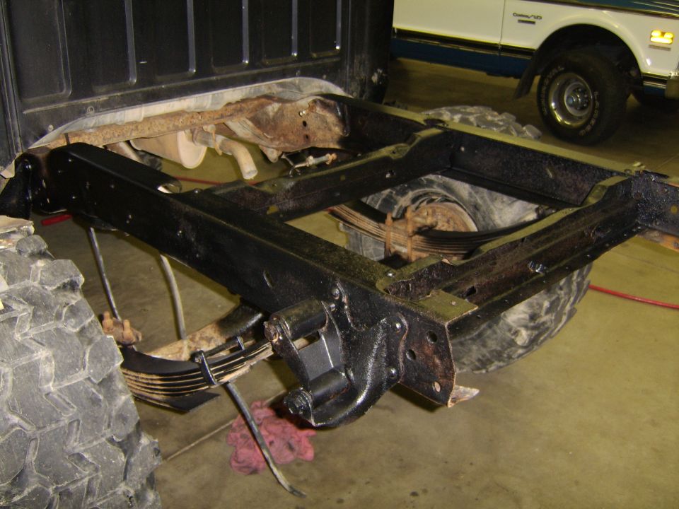 Rear frame and leaf springs of a truck, with another truck in the background