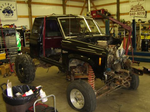 1986 Ford Ranger - A black 1986 Ford Ranger truck is undergoing repairs in a workshop, with its engine removed and body panels open.