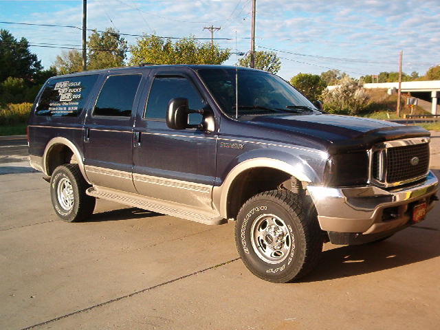 Dark blue two-tone Ford Excursion, front three-quarter view on concrete lot