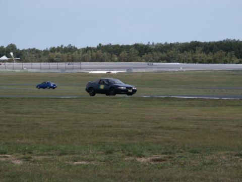 2001 Mercury Grand Marquis - A dark sedan with racing number 48 drives on a track, with another blue car in the distance.