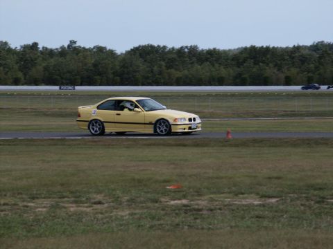 2001 Mercury Grand Marquis - A yellow BMW M3 is on the track during a race event.