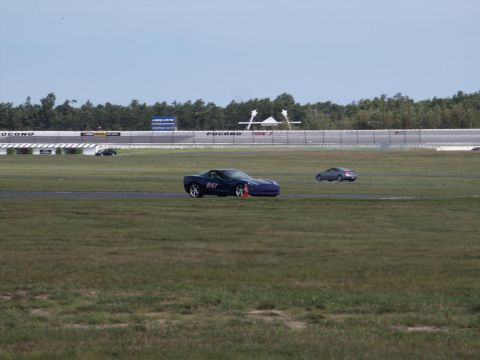 2001 Mercury Grand Marquis - Two sports cars are on a race track with trees and a grandstand in the background.