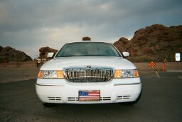 2001 Mercury Grand Marquis - A white 2001 Mercury Grand Marquis is parked in front of a rocky landscape under a cloudy sky.