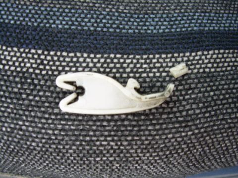 1994 Ford Bronco - A close-up view of a broken plastic clip resting on a textured fabric surface.