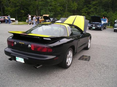 1984 Pontiac Fiero - A black 1994 Pontiac Firebird Trans Am is parked at an outdoor car show with its hood open.