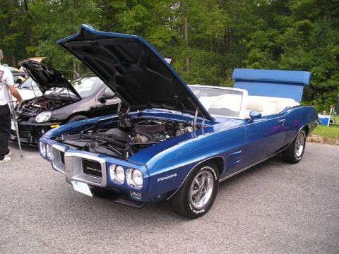 1984 Pontiac Fiero - A blue 1969 Pontiac Firebird convertible is displayed with its hood open, parked next to another car.