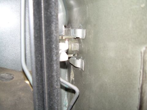 1994 Ford Bronco - Close-up view of a vehicle's interior door latch mechanism, showing metal clips and wiring.