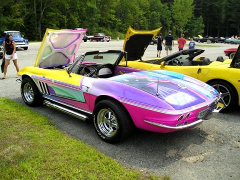 1984 Pontiac Fiero - A brightly colored classic convertible with its hood up is parked at an outdoor car show.