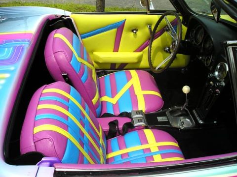 1984 Pontiac Fiero - The interior of this car features a vibrant pink, blue, and yellow striped upholstery on the seats and door panels.