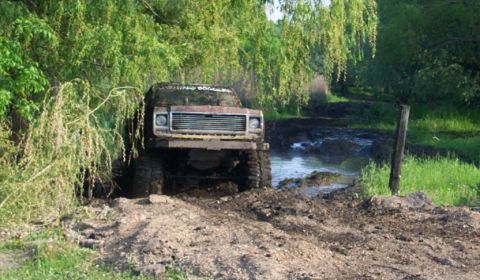 1978 Ford Bronco - Off-road vehicle navigates a muddy trail with water obstacles.