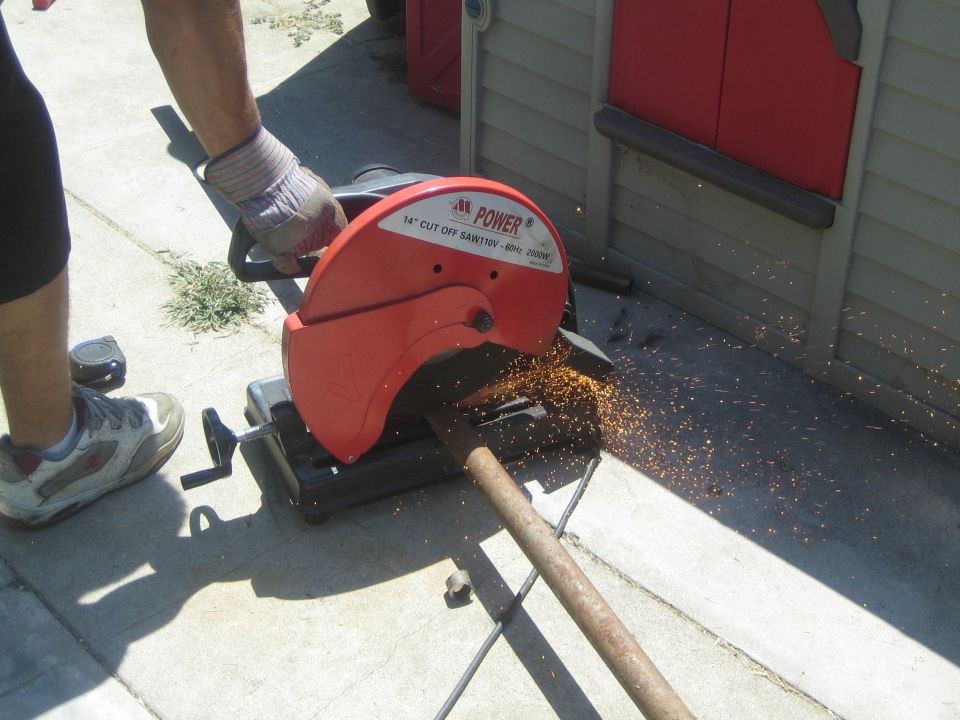 Red metal cutting saw with sparks flying, cutting a pipe