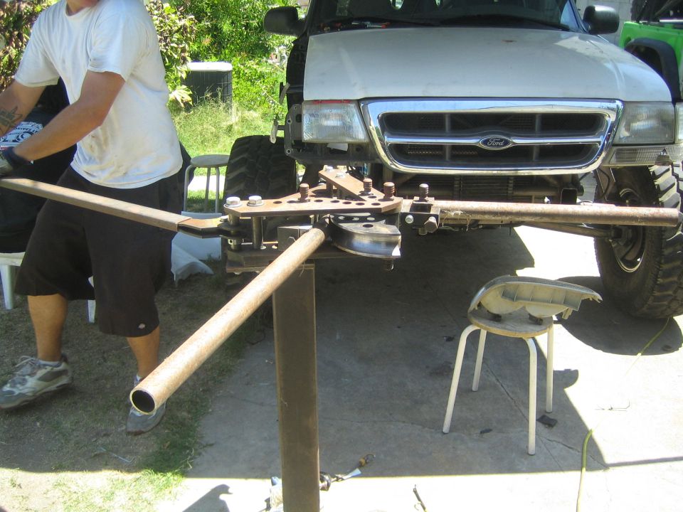 Ford Ranger front end with pipe bender attached to frame. Person in white shirt operating bender
