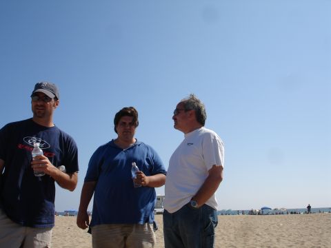 1995 Ford Taurus - Three men are standing on the beach, holding water bottles. The man on the left wears a Ford t-shirt.