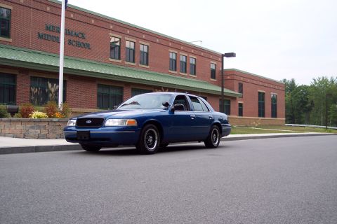 2001 Ford Crown Victoria - A blue 2001 Ford Crown Victoria is parked in front of Merrimack Middle School.