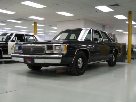 2001 Ford Crown Victoria - This Ford Crown Victoria, likely from the 1980s, is parked indoors next to another police vehicle.
