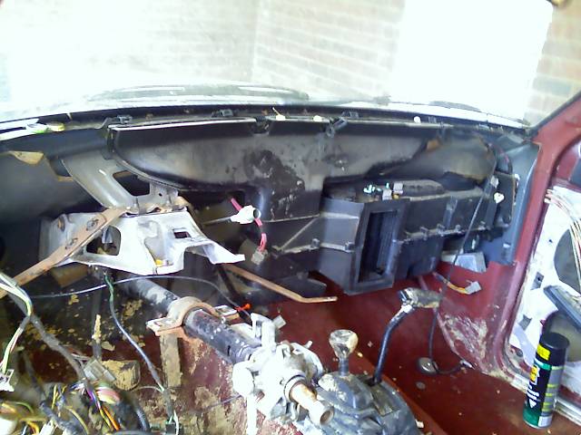 Vehicle interior with dashboard removed, showing exposed wiring and HVAC components