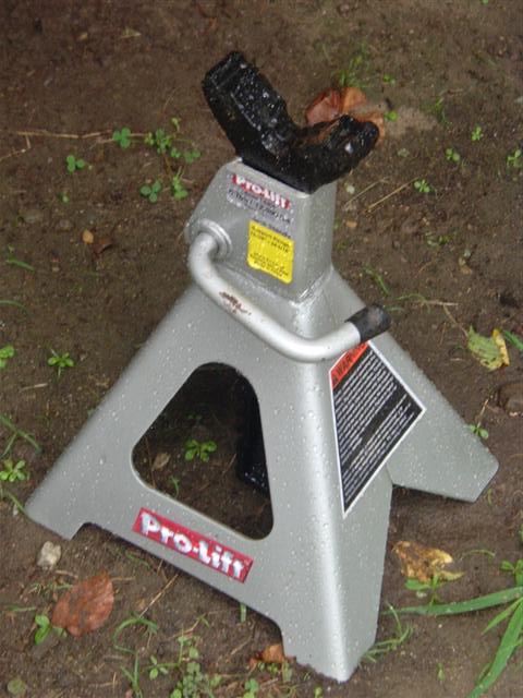 1991 Ford Bronco - A silver Pro-Lift jack stand sits on wet ground, showing its warning label and brand name.
