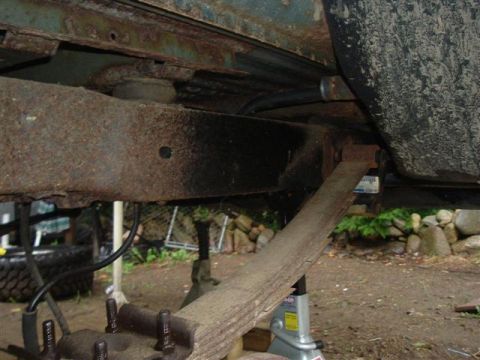 1991 Ford Bronco - Close-up view of the rusty undercarriage, showing the leaf spring and frame components.
