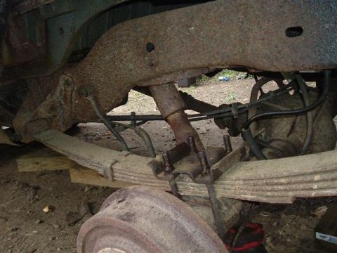 1991 Ford Bronco - Close-up of heavily rusted rear axle and leaf spring suspension components.