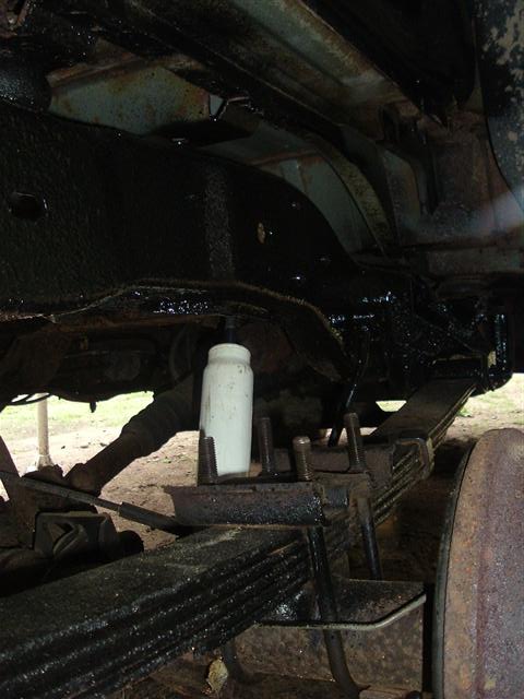 1991 Ford Bronco - The underside of a vehicle is viewed from below, revealing its suspension components and frame.