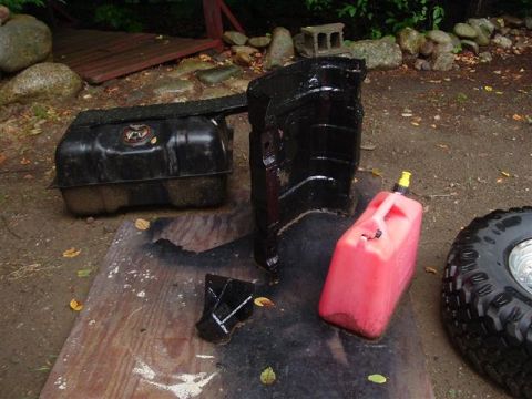 1991 Ford Bronco - Parts laid out on a wooden surface, including a fuel tank, fender liner, and gas can.