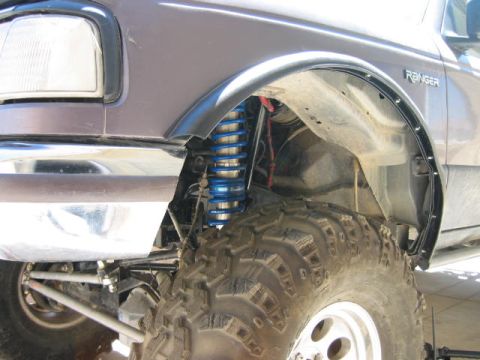1997 Ford Ranger - The front fender and suspension of a purple 1997 Ford Ranger, blue coilovers and a large off-road tire.