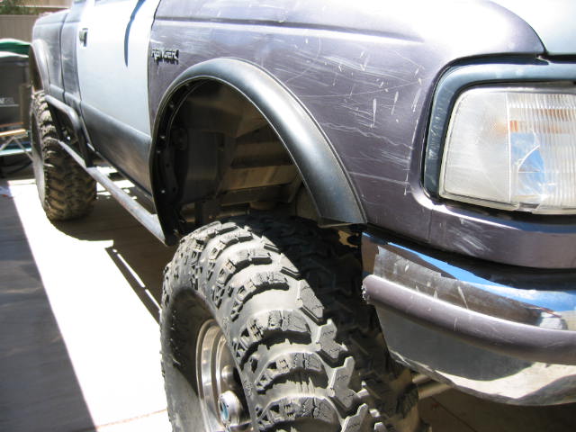 1997 Ford Ranger fender with scratches, large off-road tire, and side step