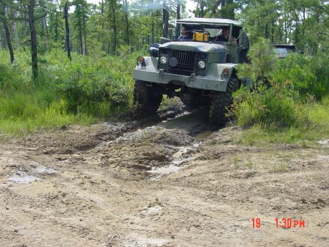 1995 Dodge 1500 - A military truck navigates a challenging muddy terrain in a wooded environment.