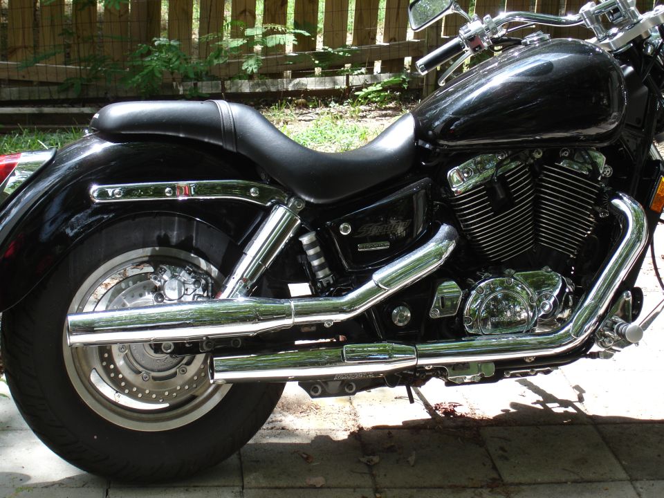 Right side view of black Honda Shadow cruiser with chrome exhaust on brick pavers.