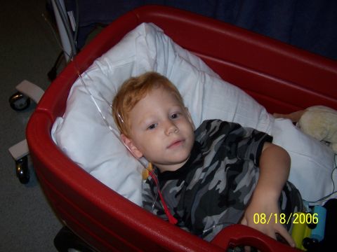 1979 Ford F-150 - A young boy with red hair rests in a red wagon, with medical equipment attached.