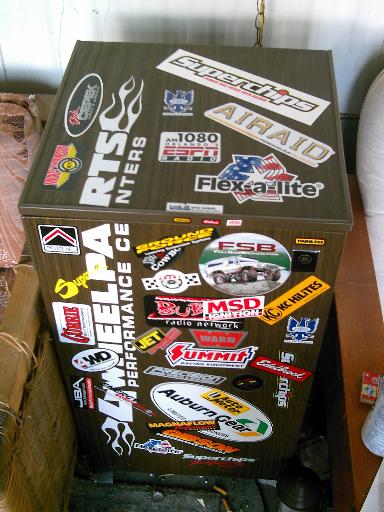 1986 Ford Bronco - A cabinet adorned with numerous automotive performance brand stickers, including Summit Racing and Auburn Gear.