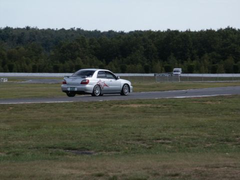 2001 Mercury Grand Marquis - Silver Subaru Impreza WRX STI on a race track with trees in the background.