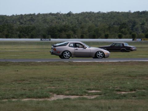 2001 Mercury Grand Marquis - A silver Porsche 944 with racing number 20 drives on a race track alongside another car.