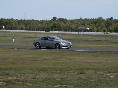 2001 Mercury Grand Marquis - A silver coupe is seen on a race track with trees in the background.