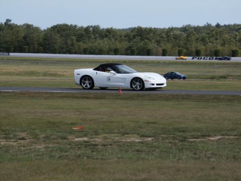 2001 Mercury Grand Marquis - A white convertible sports car navigates a race track, with another car in the background.