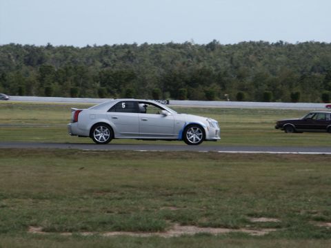 2001 Mercury Grand Marquis - A silver sedan with racing number 5 is on the track, with a dark car in the background.