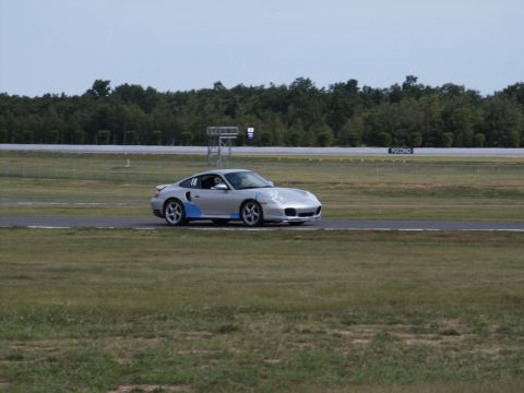2001 Mercury Grand Marquis - A silver Porsche 911 Turbo with blue accents drives on a race track under a cloudy sky.