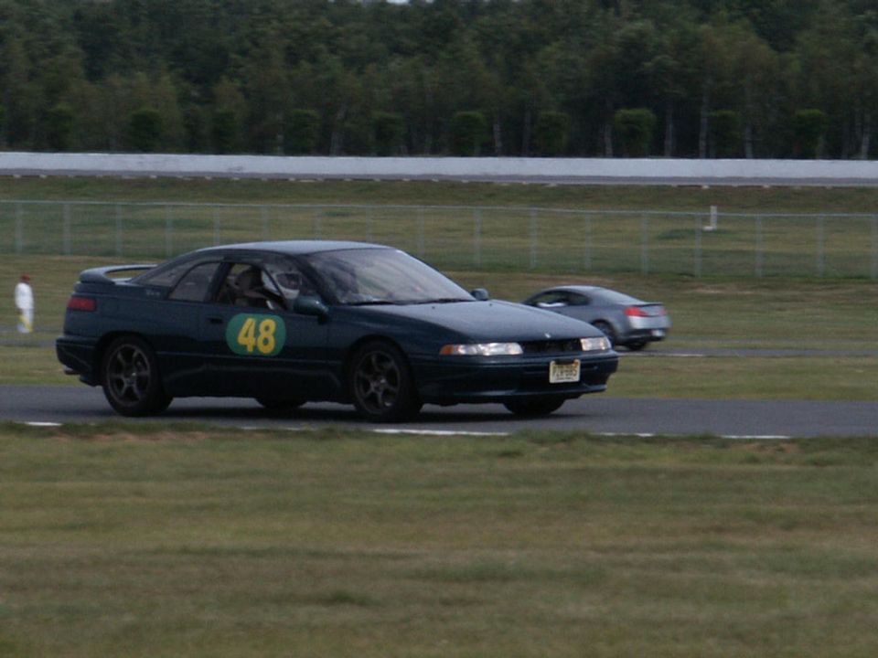 Dark green coupe with racing number 48 on the door, on a race track with another car in the background