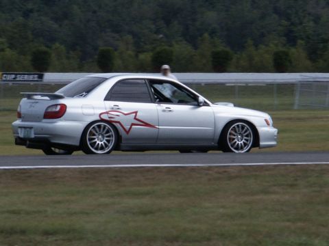 2001 Mercury Grand Marquis - Silver Subaru Impreza WRX STI sedan with a red star graphic on the side is seen on a race track.